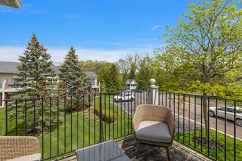 A chair is on a table on a balcony overlooking a street.